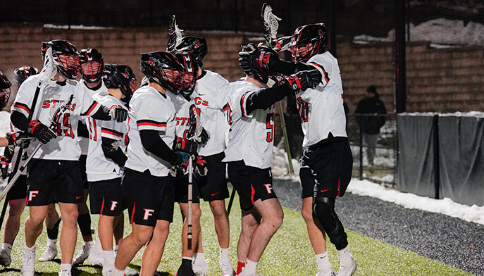 Fairfield University Lacrosse players in a huddle, celebrating their success on the field with enthusiasm and camaraderie.  