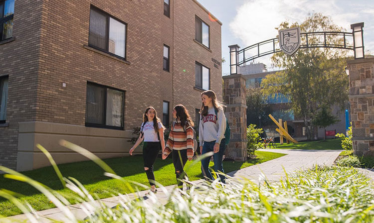 Three students walking through campus on a sunny day. 